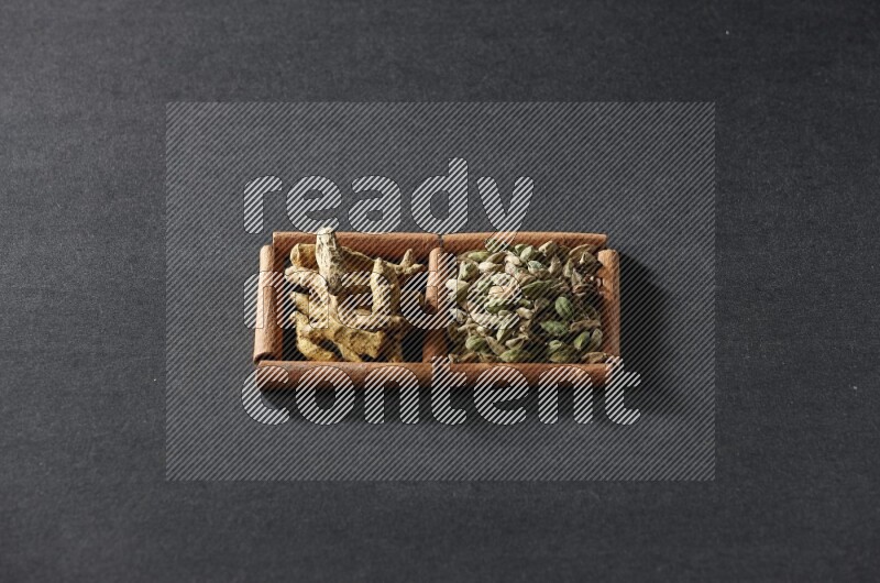 2 squares of cinnamon sticks full of cardamom and turmeric fingers on black flooring