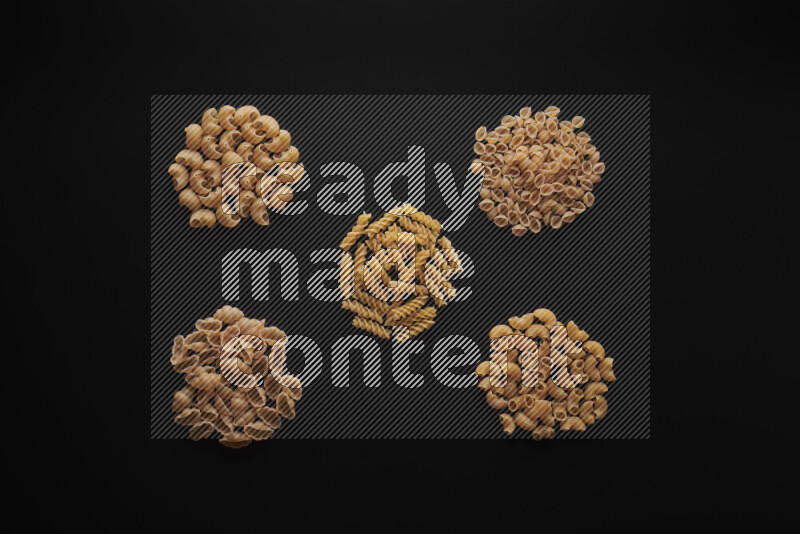 Different pasta types in bunches on black background