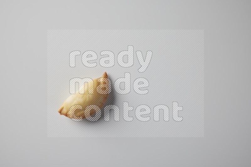 One fried sambosa from a top angle on a white background