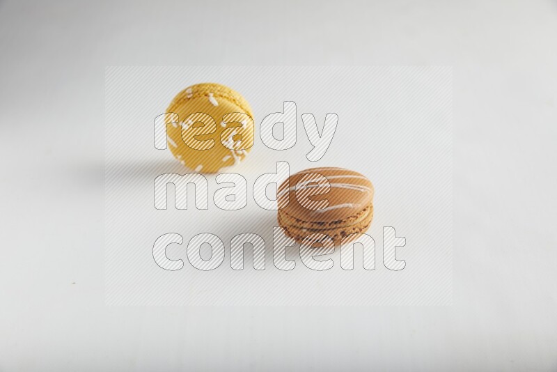 45º Shot of of two assorted Brown Irish Cream, and Yellow Piña Colada macarons on white background