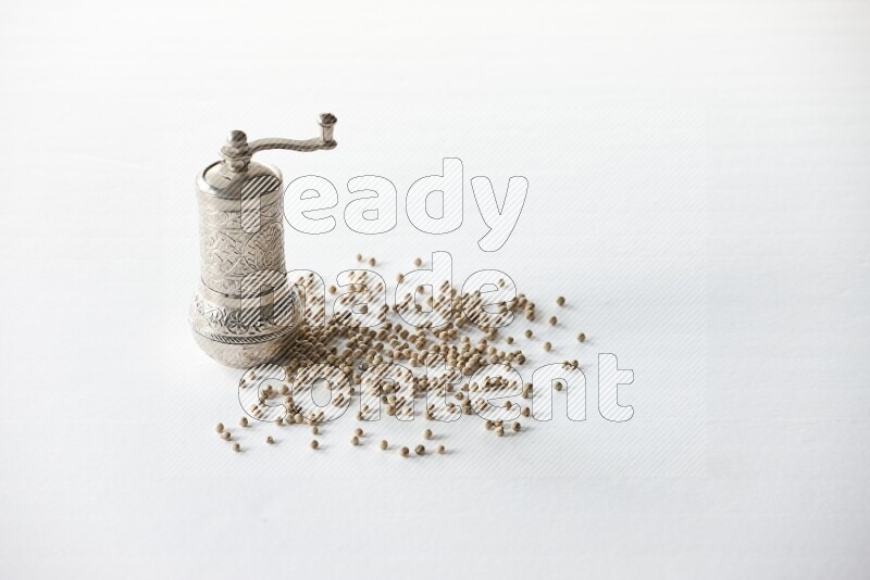 White pepper beads with a metal grinder on white flooring