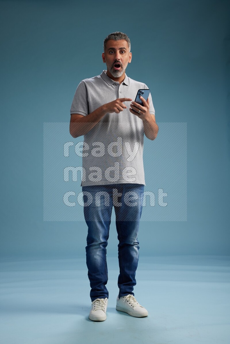 Man Standing texting on phone on blue background