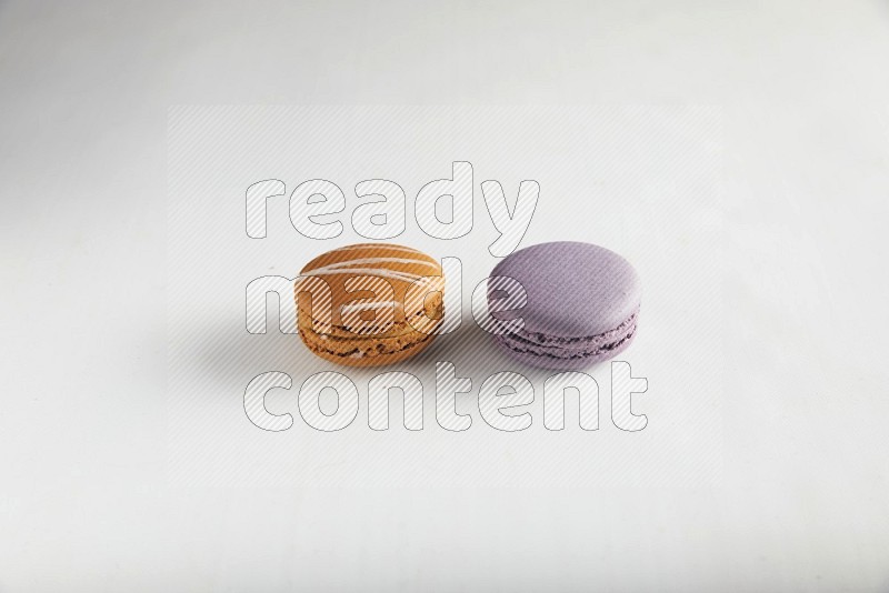 45º Shot of of two assorted Brown Irish Cream, and Purple Blueberry macarons on white background