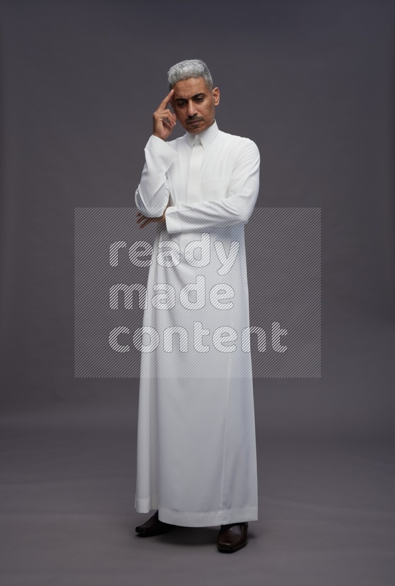 Saudi man wearing thob standing interacting with the camera on gray background