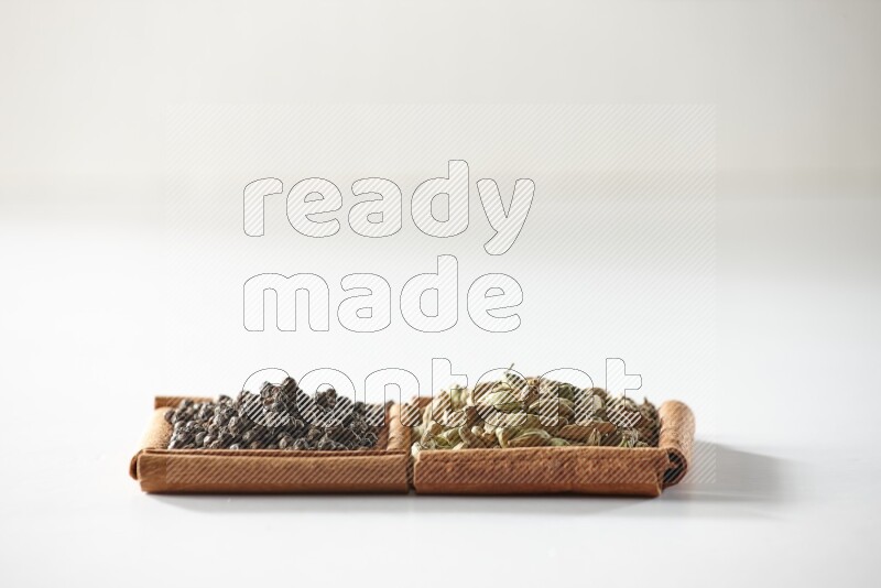 2 squares of cinnamon sticks full of cardamom and black pepper on white flooring