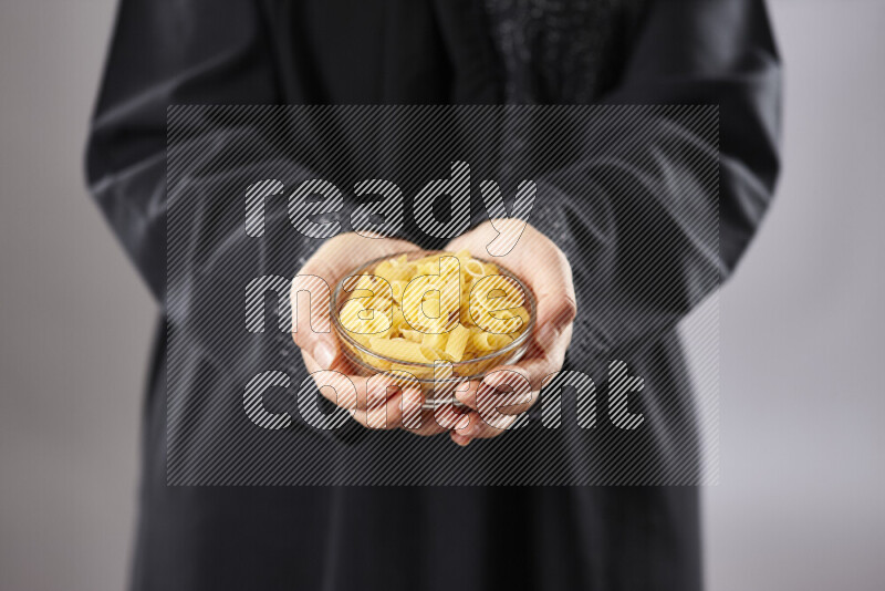 Woman in abaya holding different kinds of pasta in different positions