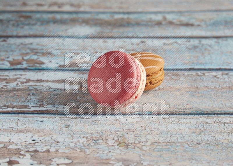 45º Shot of of two assorted Brown Irish Cream, and Pink Litchi Raspberry macarons on light blue background