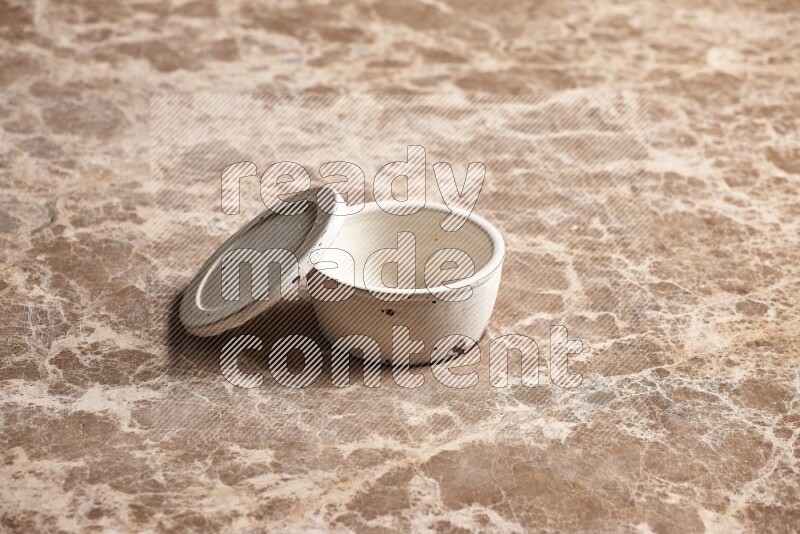 A white pottery bowl on beige marble background