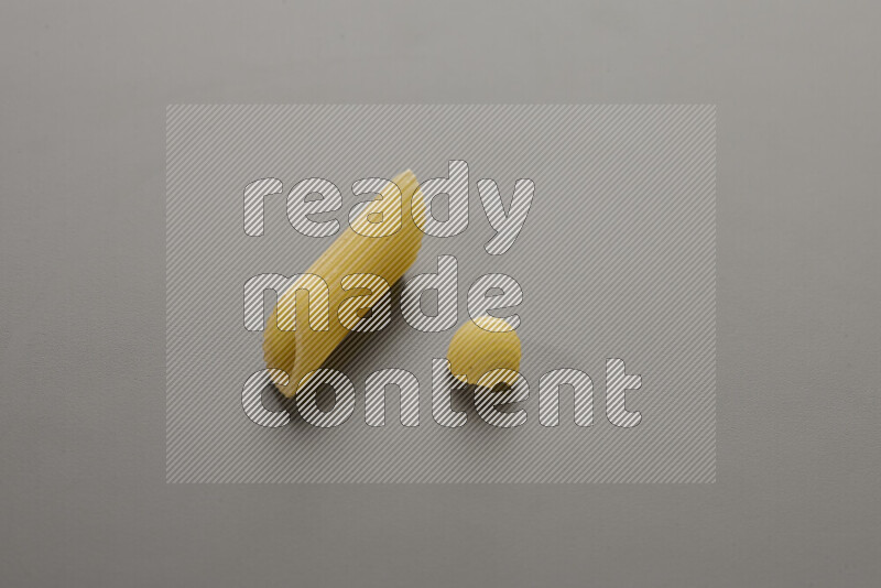Penne pasta with other types of pasta on grey background