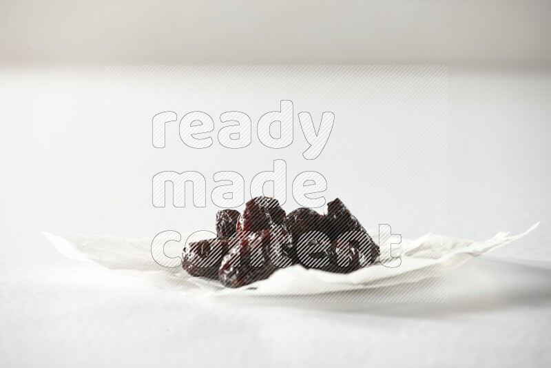 Dried plums on a crumpled piece of paper on a white background in different angles