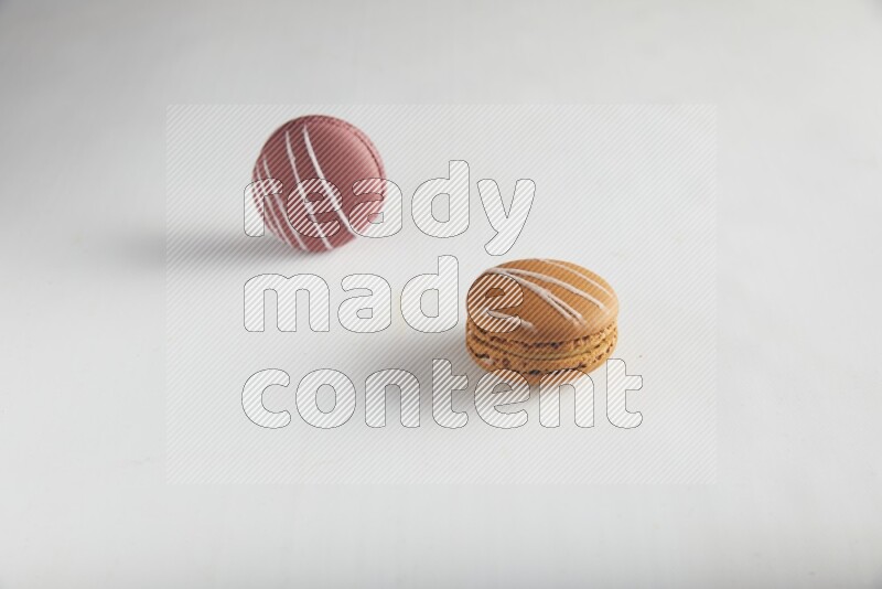 45º Shot of of two assorted Brown Irish Cream, and Red Poppy Flower macarons on white background