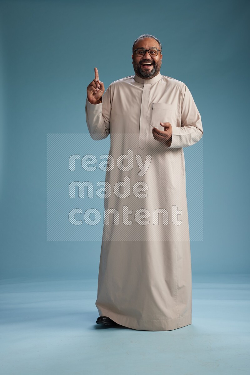 Saudi Man without shimag Standing Interacting with the camera on blue background