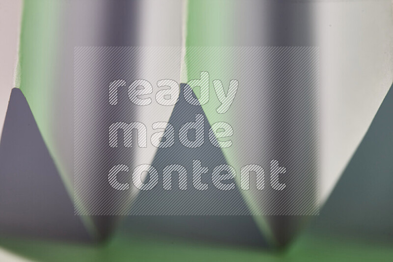 A close-up abstract image showing sharp geometric paper folds in white and green gradients