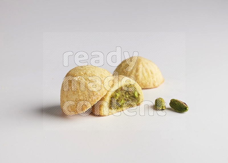 Three Pieces of Maamoul filled with pistachio paste  one of them is cut direct on white background