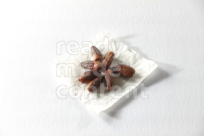 Dried dates on a crumpled piece of paper on a white background in different angles