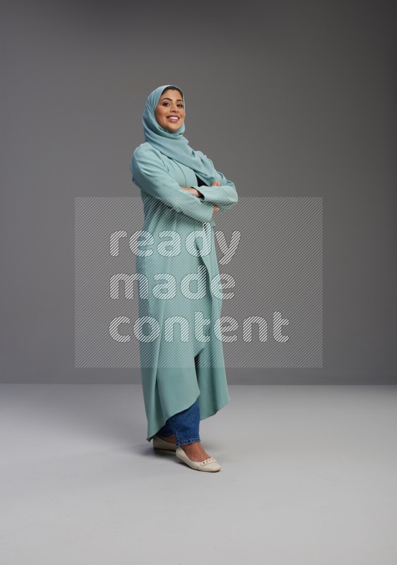 Saudi Woman wearing Abaya standing with crossed arms on Gray background