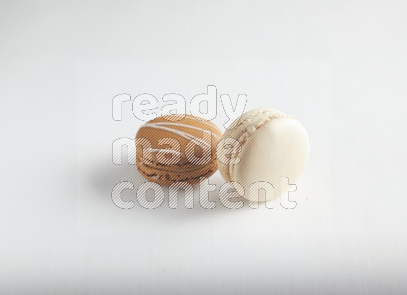 45º Shot of of two assorted Brown Irish Cream, and White Caramel fleur de sel macarons on white background