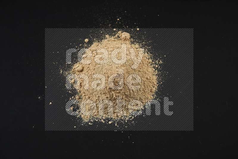 A bunch of ground ginger powder on black background