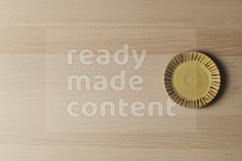 A multicolored pottery plate on light wooden background