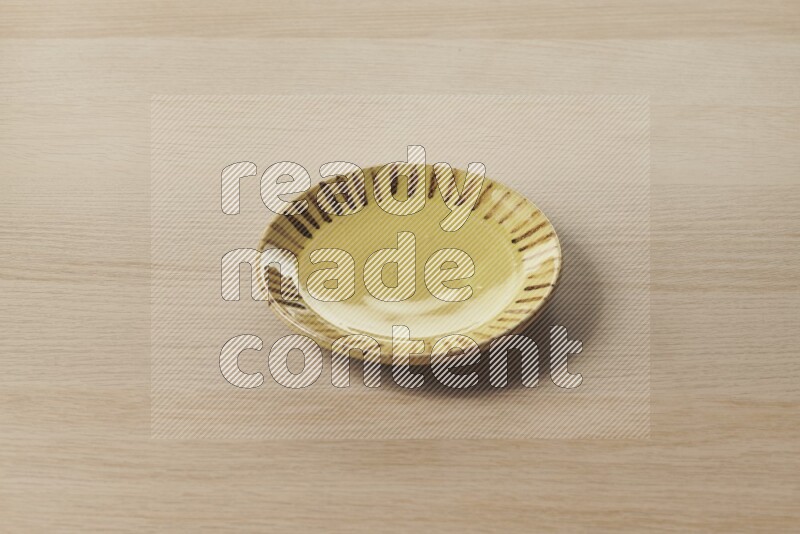 A multicolored pottery plate on light wooden background