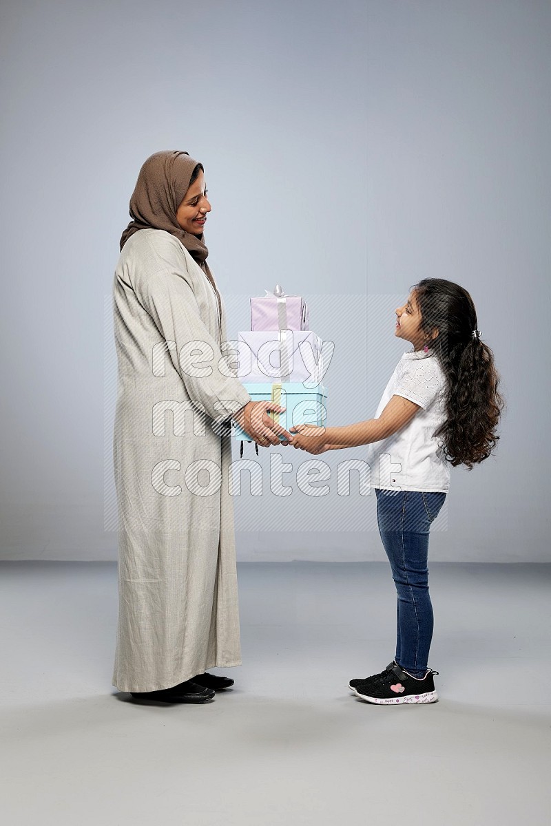 A girl giving a gift to her mother on gray background