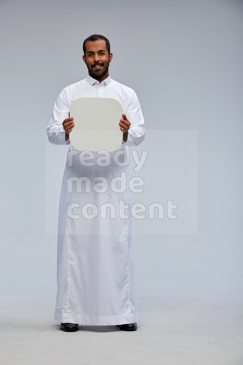 Saudi man wearing Thob standing holding social media sign on Gray background