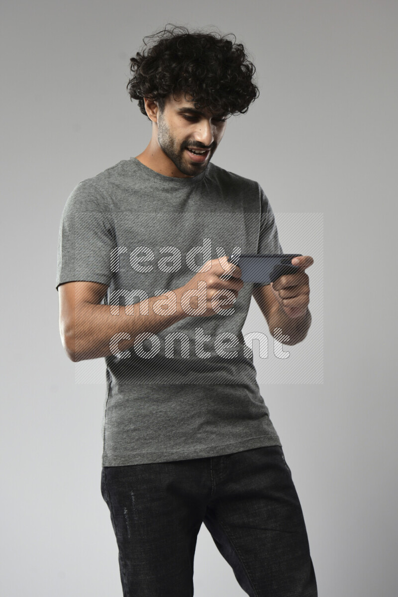 رجل يرتدي ملابس كاجوال يلعب علي الهاتف علي خلفية بيضاء