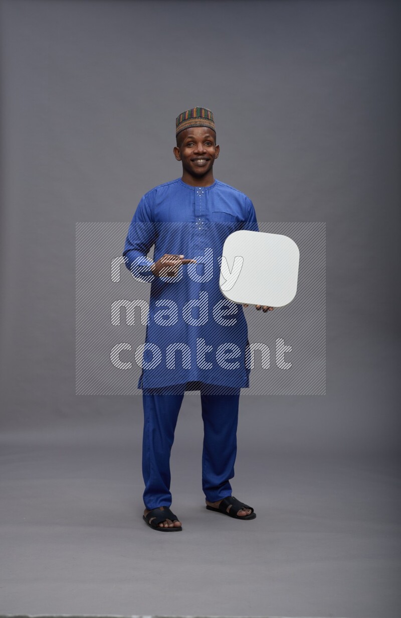 Man wearing Nigerian outfit standing holding social media sign on gray background