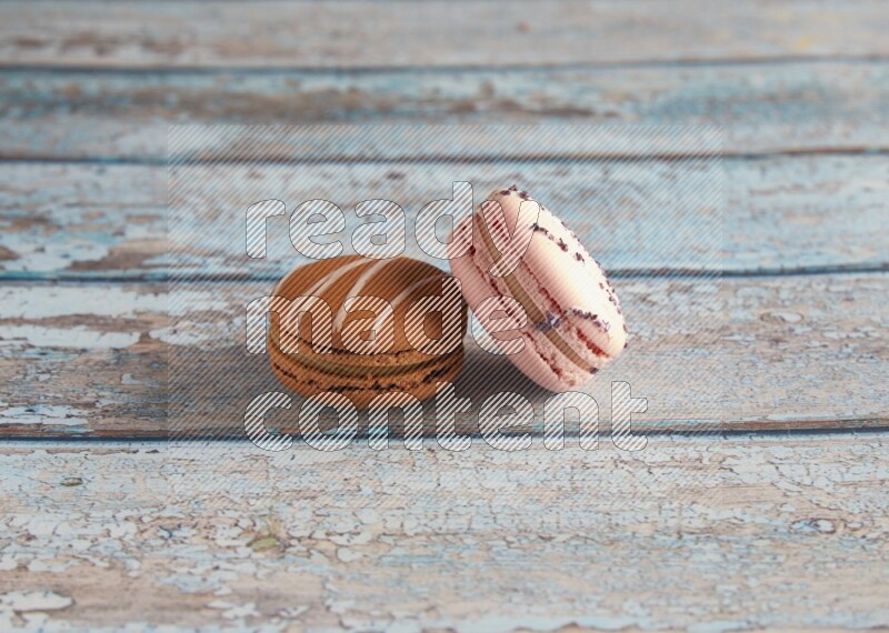 45º Shot of of two assorted Brown Irish Cream, and pink orange blossom  macarons on light blue background