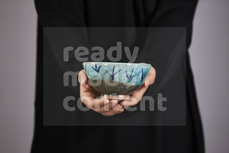 A woman in black abaya holding different pottery essentials in different positions