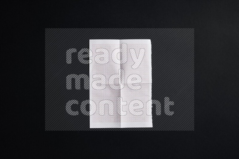 Folded notebook sheet on black background