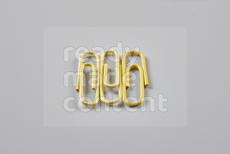 Yellow paperclips isolated on a grey background