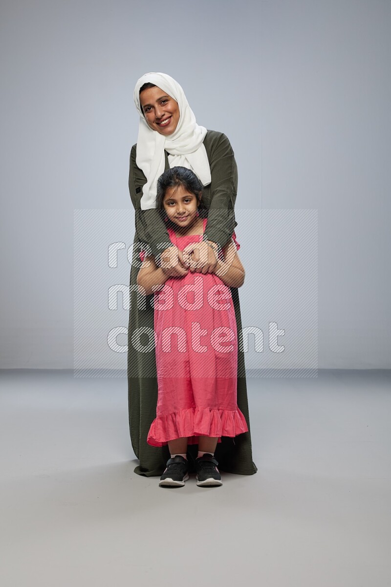 A girl and her mother interacting with the camera on gray background