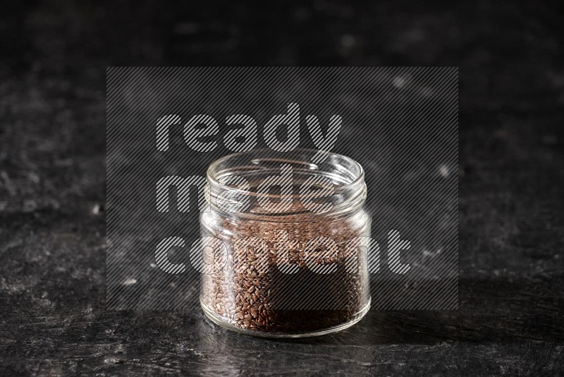 وعاء زجاجي ممتلئ بحبوب بذر الكتان علي خلفية سوداء