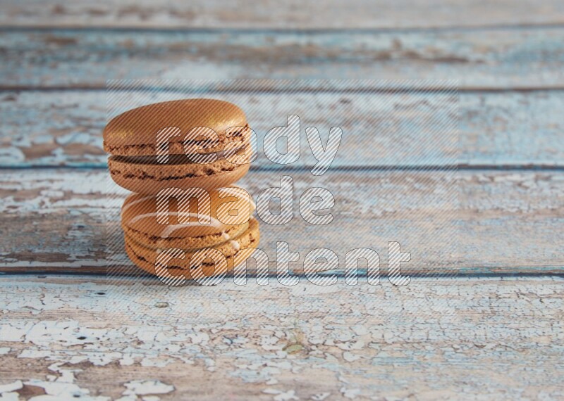 45º Shot of of two assorted Brown Irish Cream, and Brown Coffee macarons on light blue background