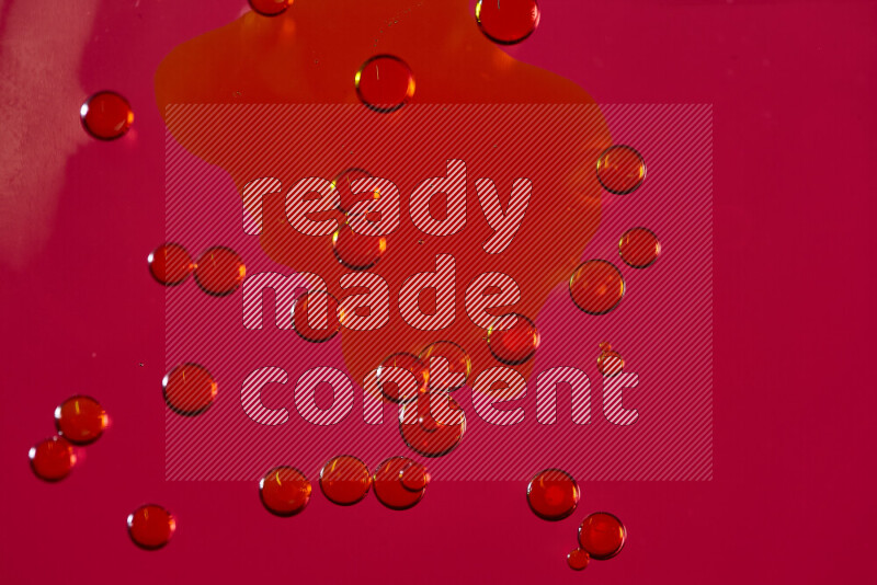 لقطات مقربة لقطرات ألوان مائية صفراء على سطح الزيت على خلفية حمراء