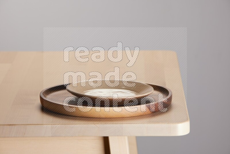 multi-colored pottery Plate placed on a light colored wooden tray on the edge of wooden table