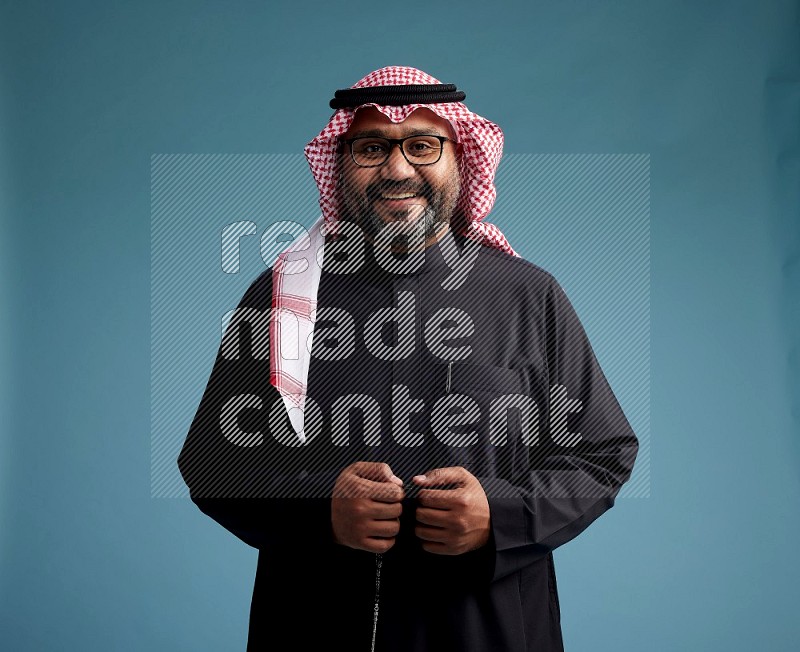 Saudi Man with shimag Standing Interacting with the camera on blue background