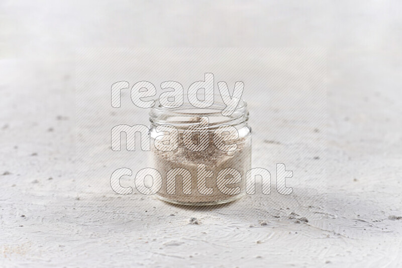 A glass jar full of onion powder on white background