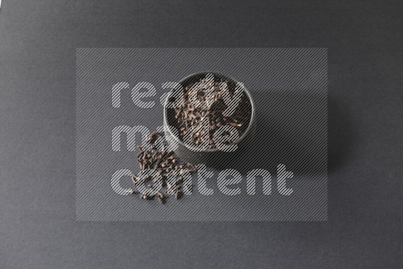 وعاء فخاري أسود ممتلئ بحبوب القرنفل علي خلفية سوداء