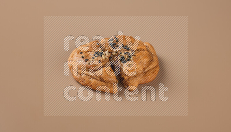 a Hasawi cookie field of date and herbs with another one cut in half on a brown background
