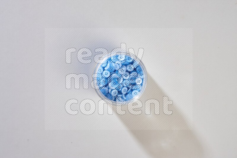 أزرار ملونة في وعاء زجاجي على خلفية رمادية