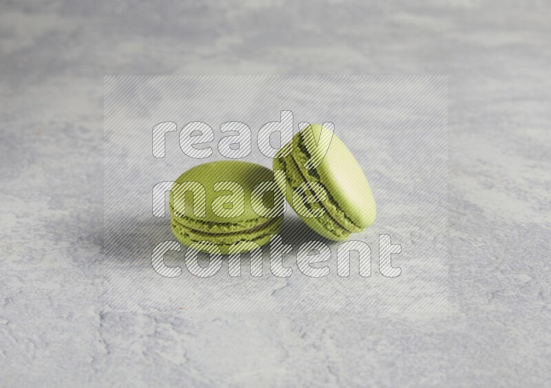 45º Shot of two Green Pistachio macarons  on white  marble background