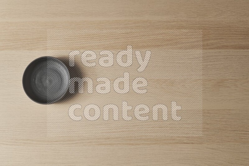 A black pottery bowl on light wooden background