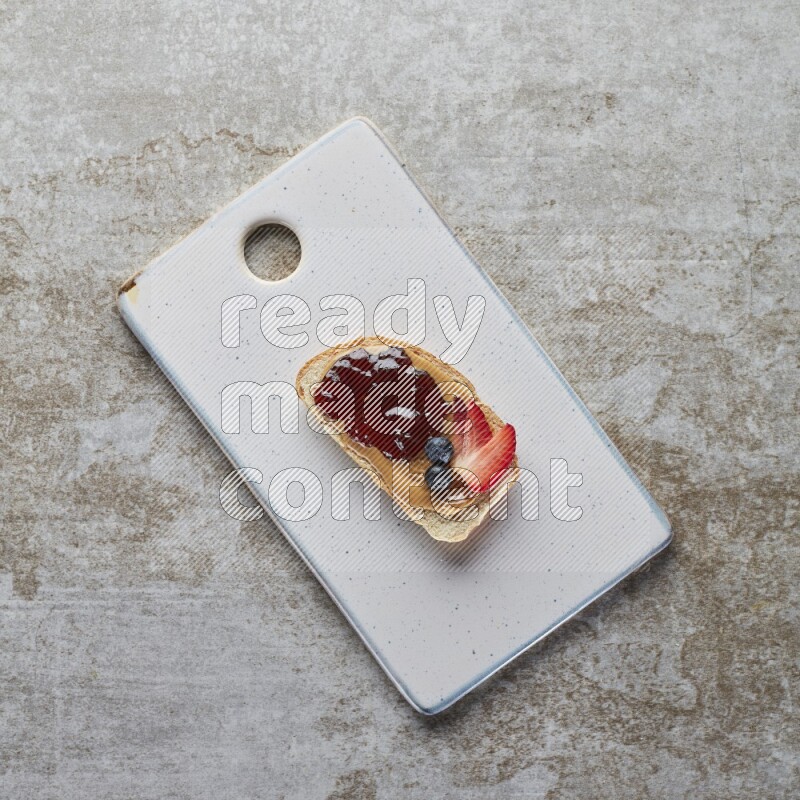 open faced peanut butter sandwich with jam, strawberries and blueberries & chia on a  grey textured background
