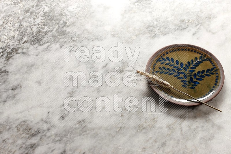 Wheat stalks on Decorative Pottery Plate on grey marble flooring, 45 degree angle