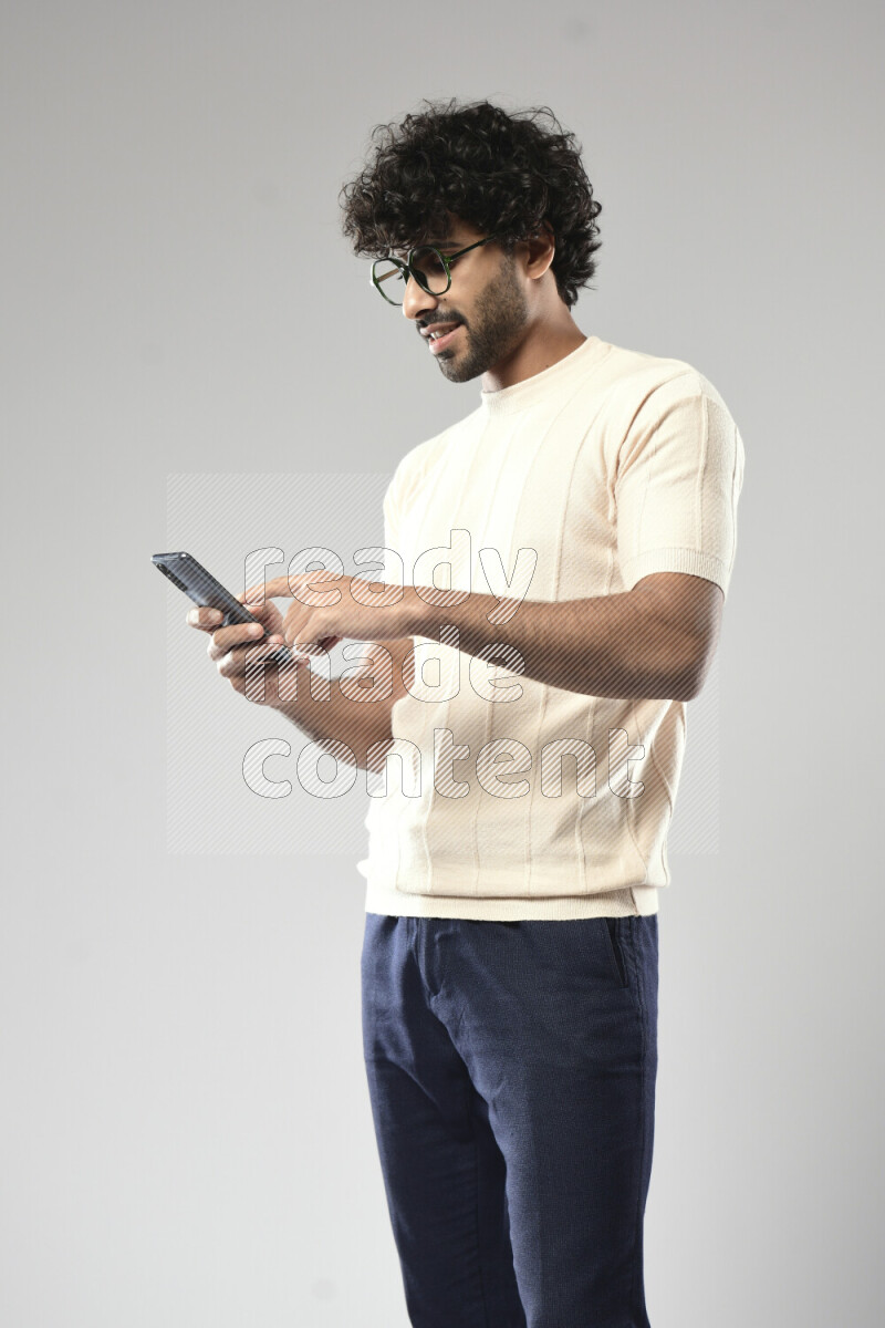 A man wearing casual standing and browsing on the phone on white background