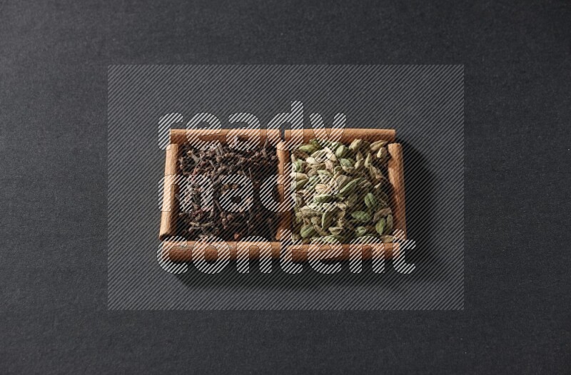 2 squares of cinnamon sticks full of cardamom and cloves on black flooring
