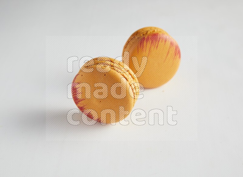 45º Shot of two orange Exotic macarons on white background