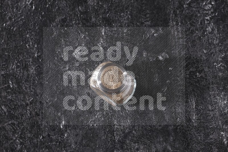 بودرة الفلفل الأسود في وعاء زجاجي علي خلفية سوداء